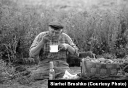 Un bărbat cu dizabilități ia o pauză de la munca de strâns cartofi pentru vecini. Districtul Khoynitsky, regiunea Homel, 1996.