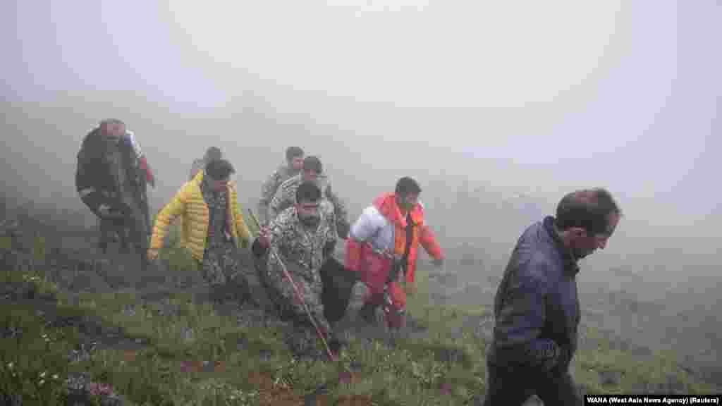 Rescuers recover bodies at the site where a helicopter carrying Iranian President Ebrahim Raisi crashed in a fog-shrouded mountainous area of northwest Iran on May 20. Raisi, 63, and his companions, including Foreign Minister Hossein Amir-Abdollahian, have been found dead at the site of the crash. 