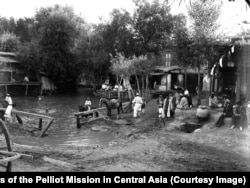 Locals swim in Tashkent. Two unidentified members of the French expedition (far right) watch the summer scene.