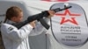 Агітаційниця тримає макет автомата АК-74 на мобільному пункті вербування у лави російської армії в окупованому Росією Сімферополі. Окупований Крим, 15 квітня 2023 року