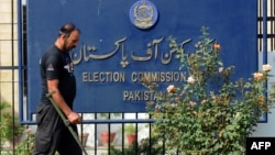 یو امنیتي سرتېری د انتخاباتي کمېشن ودانۍ مخې ته د چوونکو موادو لټون کوي- پخوانی انځور.