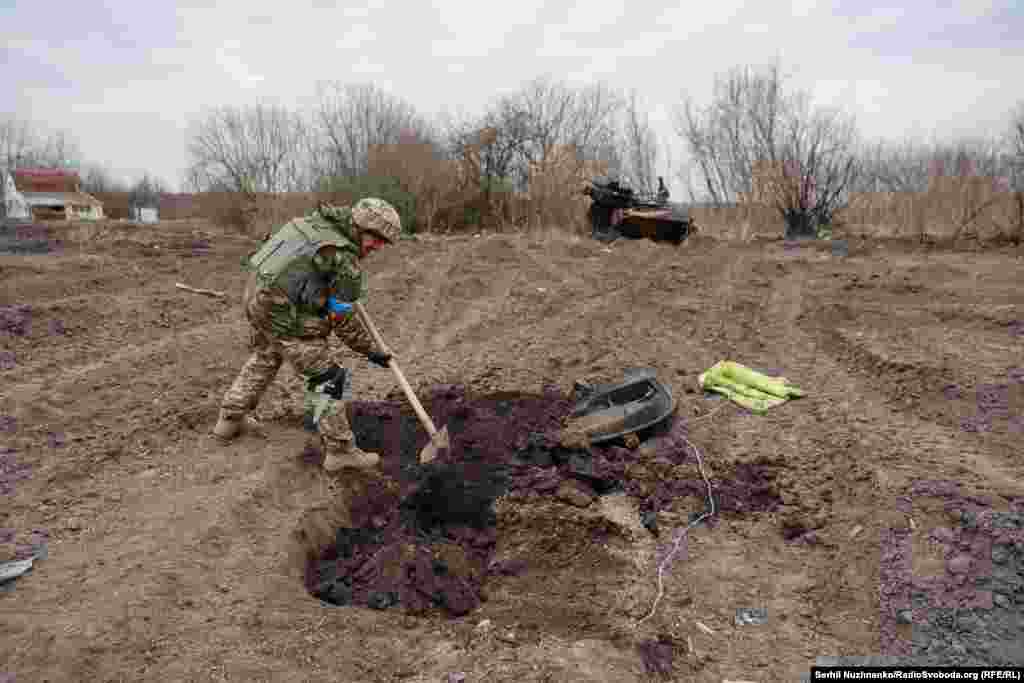 Український військовий ховає останки тіла російського солдата (щоб не розтягували собаки) у нещодавно звільненому селі Лук&#39;янівка на Київщині, березень 2022 року / Світлина праворуч від березня 2024 року