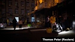 Rusiyanın Ukraynaya hücumu fonunda elektrik enerjisinin qismən kəsilməsi zamanı insanlar supermarketi fənərlərlə tərk edirlər.