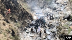 Security officials inspect the wreckage of a vehicle that was carrying Chinese nationals and plunged into a ravine after a suicide attack near Besham city in the Shangla district of Khyber Pakhtunkhwa Province on March 26.