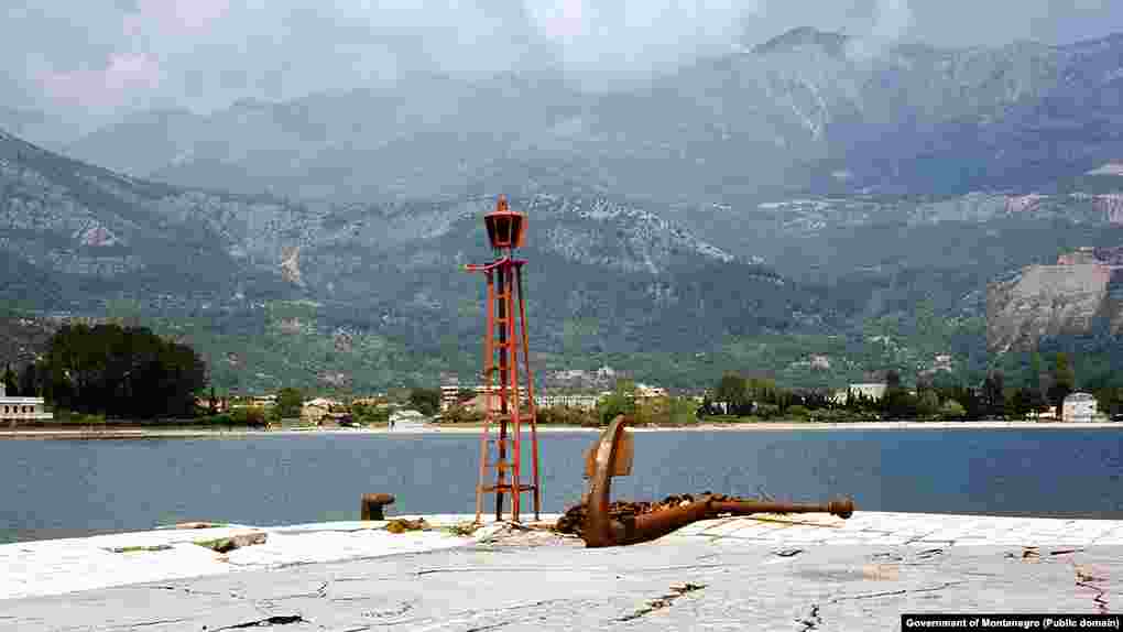 Pogled sa svjetionika Pizane, dijela budvanskog pristaništa do kojeg je 1979. vodila od potresa napukla riva. Pogled na zaleđe Slovenske plaže "ukrašavaju" betonski mastodonti, na samoj "pjeni od mora". 