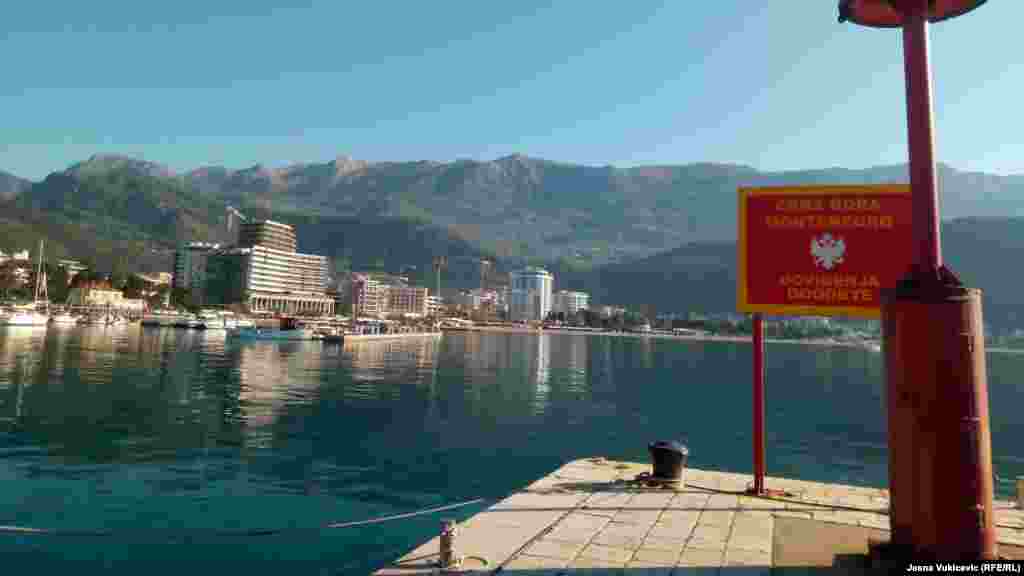 Pogled sa svjetionika Pizane, dijela budvanskog pristaništa do kojeg je 1979. vodila od potresa napukla riva. Pogled na zaleđe Slovenske plaže "ukrašavaju" betonski mastodonti, na samoj "pjeni od mora". 