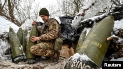 Украински войник подготвя 155 мм снаряди близо до фронтовата линия, 14 януари 2024 г.