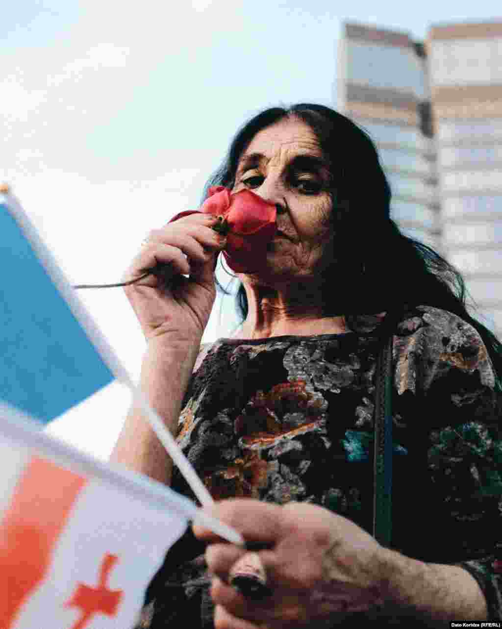 Учасниця протесту з трояндою в руках очевидно хоче нагади «Революцію троянд» у Грузії, коли у 2003-му році відбулася безкровна зміна влади. Президентка Саломе Зурабішвілі сказала, що її найбільше хвилює той факт, що законопроєкт є «точною копією закону (президента Росії Володимира) Путіна»