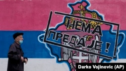 Čovek prolazi pored grafita koji prikazuje mapu Kosova i srpski grb i zastavu na kojoj piše: "Nema predaje!", Beograd, 26. april 2023.