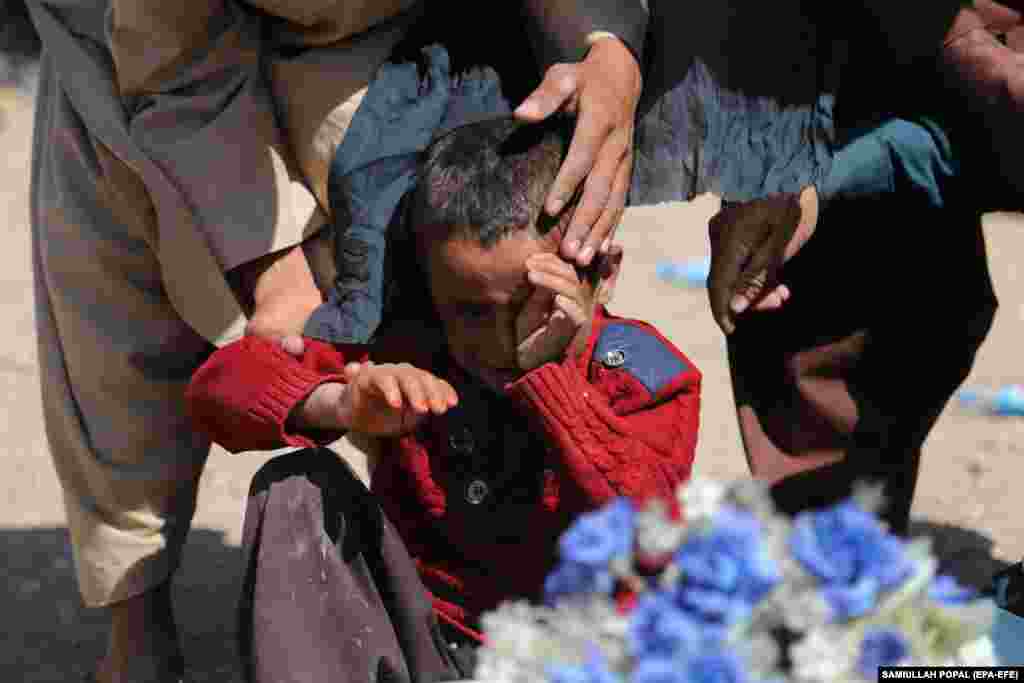 A boy reacts next to the body of his sister who was killed in an earthquake. 