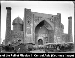 A rare view of Registan Square, the historic center of Samarkand, filled with market stalls. Above the arch are the two iconic leopards of the Sherdor Madrasah.