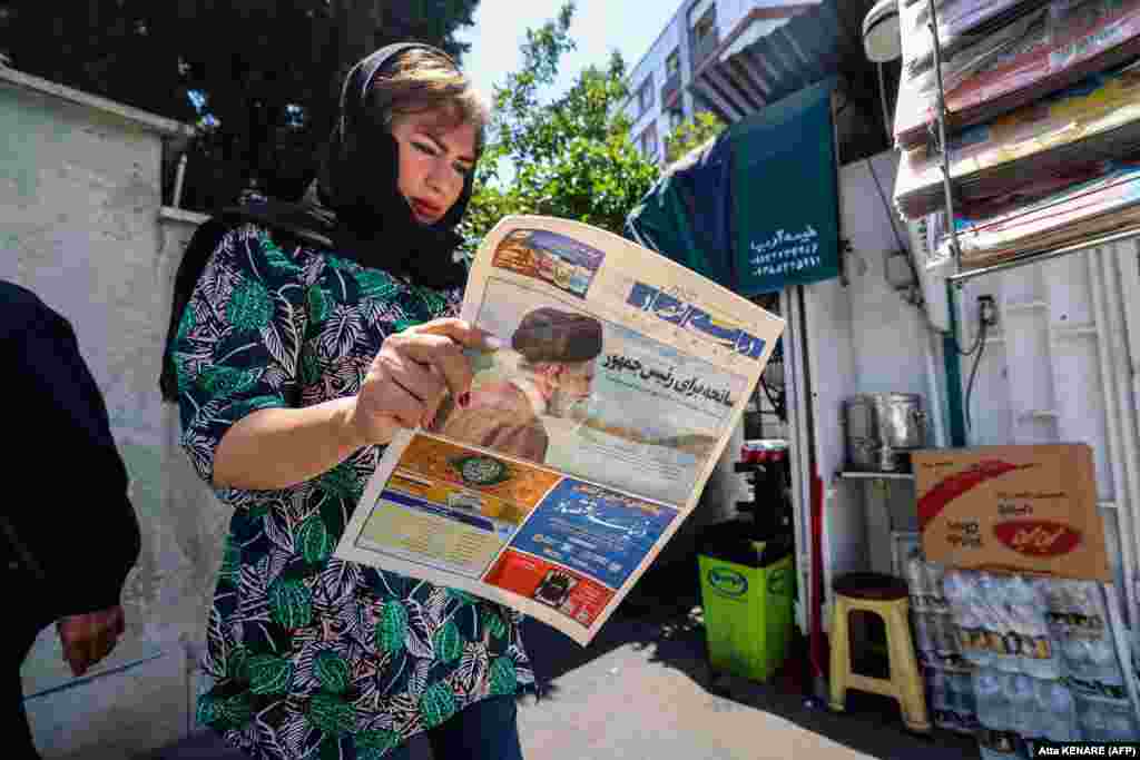 An Iranian woman reads a newspaper with a front-page report on the crash. 