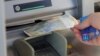 Muškarac podiže srpski dinar sa bankomata u Mitrovici, Kosovo, 1. februara 2024.