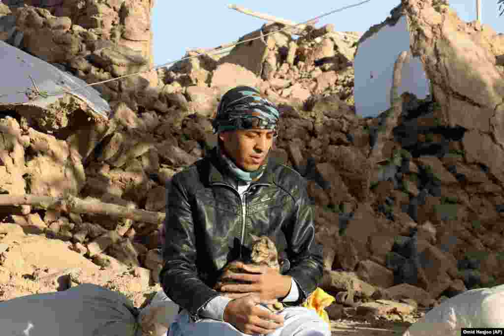  An Afghan youth holds his cat as he sits in a courtyard of his destroyed home. Mullah Janan Sayeeq, a spokesman for the Taliban's Ministry of Disasters, told a news conference that 2,440 people were dead, about 10,000 were injured, and that more than 2,000 houses had been damaged or destroyed. Afghanistan's disaster agency said on October 8 that 2,053 people had been killed. Neither estimate could be independently confirmed.