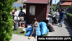 Ukrajinske izbeglice iz Zakarpatja sede na trotoaru blizu svog bivšeg skloništa u selu Koč, oko 70 km severozapadno od Budimpešte, 21. avgust 2024. 