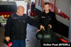 Viktor Danylenko and Oleh Samoylenkov, with 23 and 24 years on Kharkiv's fire department, respectively, show off a flak jacket, a wartime addition to their typical gear.