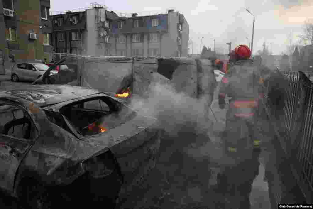 Emergency workers extinguish fires from the site of a Russian missile strike in Kyiv.
