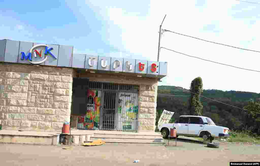 An abandoned vehicle is parked in front of a closed shop in Xankendi on October 2. The exodus of the region's people followed a 24-hour campaign that began on September 19, when Azerbaijani forces routed the region's undermanned and outgunned Armenian forces, forcing them to capitulate. 