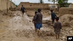 People walk near their damaged homes after heavy flooding in Baghlan Province in northern Afghanistan on May 11.