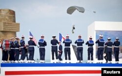 Парашутист прибуває під час гри музикантів французького флоту в Омаха-Біч з нагоди 80-ї річниці висадки союзників в Нормандії. Франція, 6 червня 2024 року