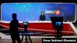 A cameraman films a news anchor at Tolo News studio.