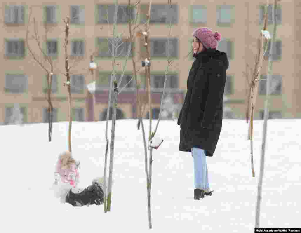 A woman wearing a woollen hat watches two dogs playing in a park in Tehran on December 24. A recent report from IRNA, an official Iranian news agency describes five businesses in Iran's northwestern Qazvin province being temporarily shut down in punishment for serving women who were not wearing hijabs. 