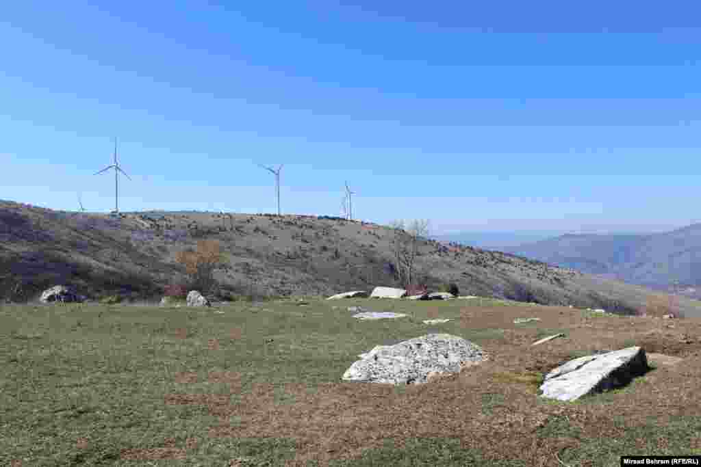 Nekropola stećaka kod sela Dobrč, najzapadnija od nekropola na platou Podveležja; na slici se u pozadini vidi nedavno izgrađeni vjetropark Podveležje. 