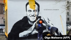 Навальныйдын элеси түшкөн муралды өчүрүп жаткан жумушчу.