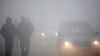 Ljudi hodaju kroz gusti smog u Kaknju, gradu u Bosni i Hercegovini