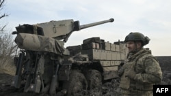 Український військовослужбовець Десантно-штурмових військ стоїть поруч із колісною самохідною гаубицею CAESAR 8x8 на передовій, південь України, 14 лютого 2024 року 