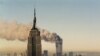 Turnurile gemene de la World Trade Center arzînd în spatele blocului Empire State Building, New York, 11 septembrie 2001.