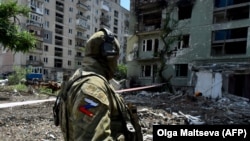 A Russian soldier patrols a destroyed residential area in the city of Syevyerodonetsk on July 12.