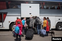 Українські біженці з Маріуполя сідають в автобус, що прямує до Польщі. Запоріжжя, Україна, 17 травня 2022 року