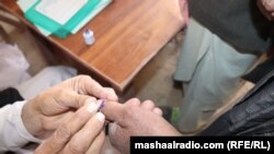په بلوچستان کې یو انتخاباتي افسر د یو ووټ اچوونکي ګوته رنګوي - پخوانی انځور.