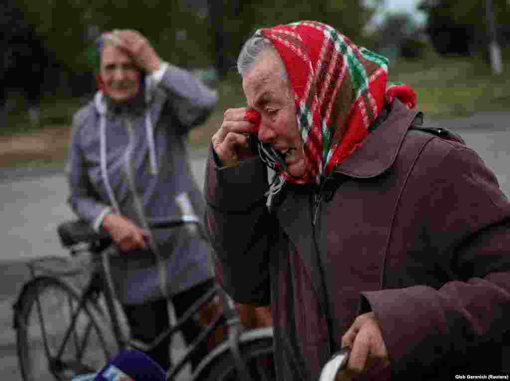 Local residents react as they wait for a car distributing humanitarian aid in the village of Verbivka, which was also recently liberated.