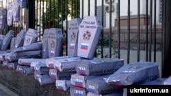 Десятки картонных гробов возле здания посольства России в Киеве.