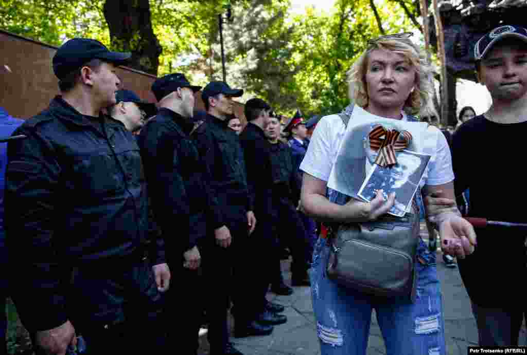 Помимо полиции в парке дежурило несколько десятков сотрудников спецназа. На фото: участница акции «Бессмертный полк» проходит мимо силовиков. Алматы, 9 мая 2019 года.