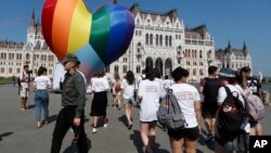 Activists walk past a large rainbow-colored heart erected in front of the country's parliament in Budapest on July 8. The activists were protesting against the recently passed law they say discriminates and marginalizes LGBT people.