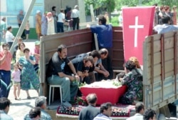 A family unloads a body from a truck during a funeral for victims in Budyonnovsk on June 16, 1995.