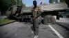 Пророссийский сепаратист стоит рядом с подорванным грузовиком у донецкого аэропорта. 29 мая 2014 года.