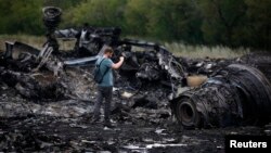 A journalist takes photographs at the site of the Malaysia Airlines Boeing 777 plane crash near the settlement of Hrabovo, in the Donetsk region, on July 18, one day after the crash, which killed all 298 people aboard.