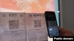 Сканирование QR-кода на смартфон с приложением Ashyq, разделяющим казахстанцев «по цветам» для пропуска в различные общественные места.