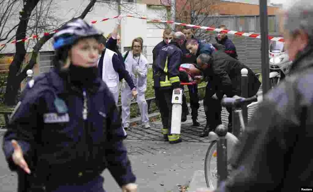 Firefighters carry a victim on a stretcher outside the publication's offices.