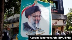 Iranians walk next to a poster depicting Iranian presidential candidate Ebrahim Raisi, an ultraconservative who is the front-runner in the June 18 vote.