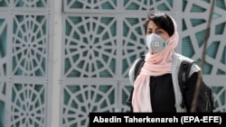 An Iranian woman wearing a face mask walks on a street in Tehran on March 2.