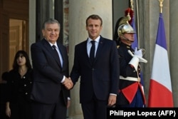 French President Emmanuel Macron (right) shakes hands with Uzbek President Shavkat Mirziyoev at the Elysee Palace in Paris on October 9.