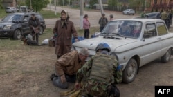 Tetyana, 75, an evacuee from the town of Vovchansk, stands next to the car in which she and her husband fled as they arrive at an evacuation point in the Kharkiv region on May 12.