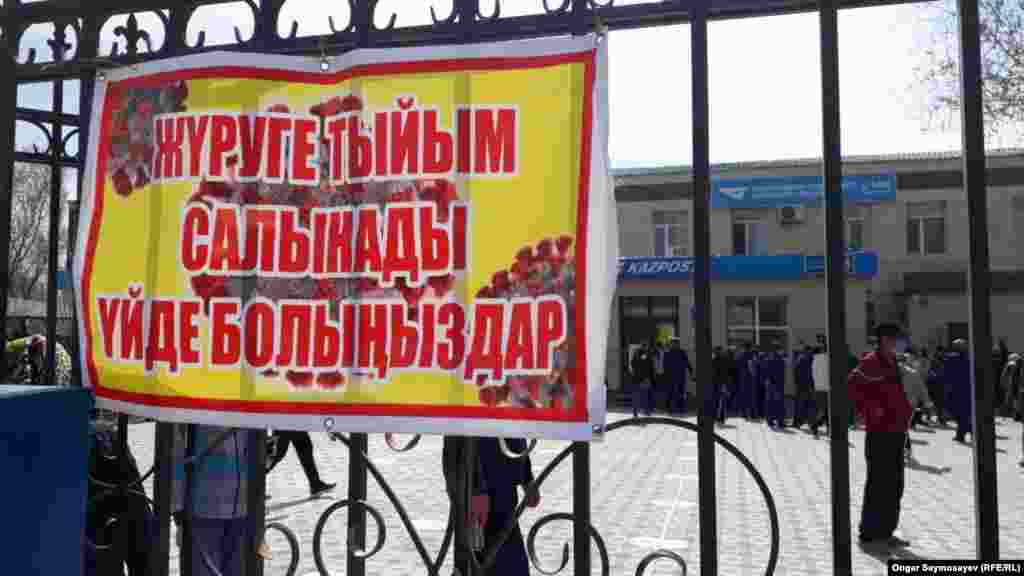 Баннер на воротах отделения Казпочты гласит: «Гулять запрещено». С самого утра у входа в это отделение собираются люди и встают в очередь. 6 апреля 2020 года. 
