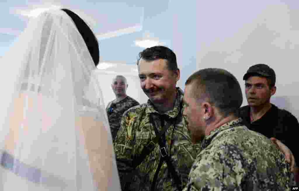 Igor Strelkov (C), commander and self-proclaimed minister of defence of the so called "Donetsk People's Republic," congratulates Motorola and Kolenkina during their wedding. 