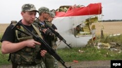 Armed pro-Russia militants walk next to the wreckage of Flight MH17 in eastern Ukraine near Donetsk on July 18, 2014.